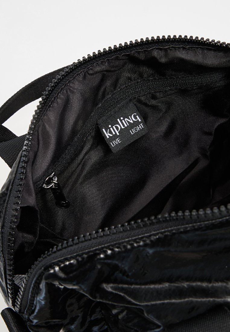 Interno della borsa Kipling nera, caratterizzato da un tessuto liscio, una tasca con zip e un'etichetta con il marchio. La zip è perfettamente allineata e funzionale.
