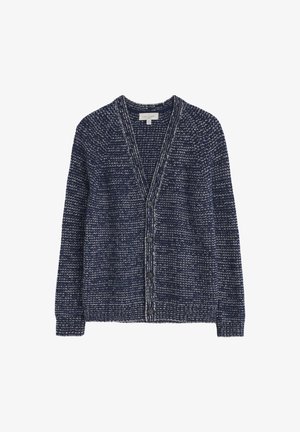 Mėlynai nusiųtas megztinis su baltais taškeliais, V formos iškirpte, ilgomis rankovėmis ir šešiais priekiniais mygtukais. Tekstūruota medžiaga su laisvu siluetu ir subtiliu gylio jausmu.