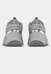 Încălțăminte sport gri cu accente metalice și talpă texturată. Prezintă elemente roz pe sigla de pe călcâi și pe curelușa cu închidere rapidă. Design rotunjit.