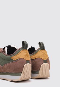 Hnědé semišové a zelené textilní sneakers s žlutým akcentem, disponující texturovanou gumovou podrážkou a poutkem na patě pro snadné nazouvání.