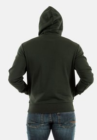 Sudadera con capucha de un verde oscuro, con una textura suave y puños acanalados. Cuenta con un bolsillo tipo canguro en la parte frontal y un diseño de corte regular.