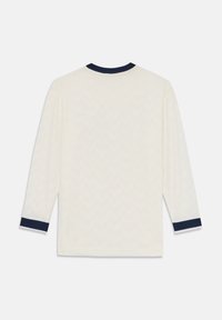 Chemise à manches longues de couleur blanc cassé avec une texture subtile en zigzag et des poignets et un col bleu marine foncé, vue de dos sur fond blanc uni.