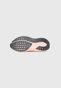 Semelle de chaussure avec un motif en caoutchouc noir texturé, formé de losanges, complétée par un design de semelle intermédiaire de couleur pêche clair.