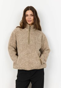 Tan fleece pullover med høj krave, kvart-lynlås foran og sidelommer. Har en struktureret, blød overflade og kontrasterende beige kant.