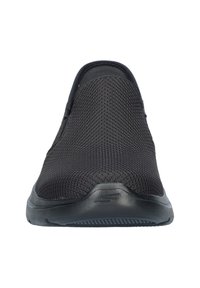 Zwarte instapsneaker van ademend gaasmateriaal, met een gestructureerd oppervlak, ronde neus en een flexibele rubberen zool.