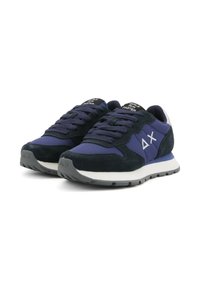Een paar marineblauwe en zwarte sneakers met een wit logo op de zijkanten en de tekst "Girls Run Faster" op de tong, schuin op een witte achtergrond.