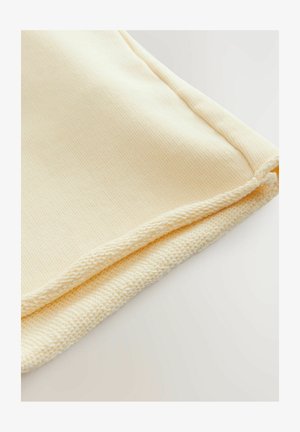 Helles gelbes Gewebe mit glatter Oberfläche, das einen sauberen Saum und einen leicht dickeren, gewebten Rand aufweist.