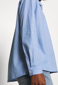 Lichtblauw overhemd met knopen, met een ontspannen pasvorm, lange mouwen en witte knopen. Gemaakt van een textuurstof. De zoom is licht gebogen.