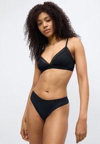 Μαύρο σουτιέν τρίγωνο με δαντέλα και υφή, σε συνδυασμό με μαύρο μαγιό σλιπ με ψηλή μέση, και τα δύο από απαλό ύφασμα.