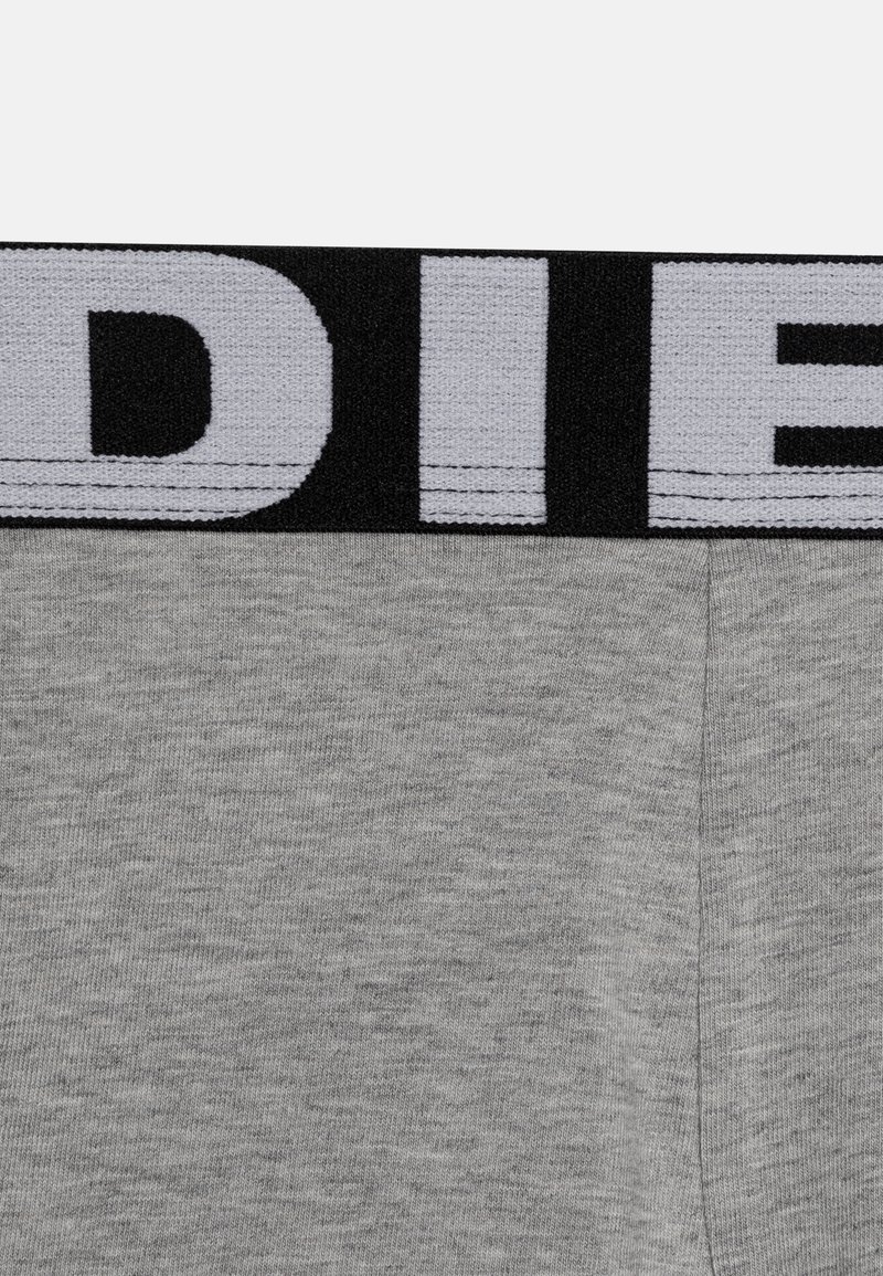 Graue Baumwoll-Boxershorts mit einem schwarzen elastischen Bund, auf dem 'DIESEL' in fetter weißer Schrift steht. Glatte Textur, figurbetontes Design.
