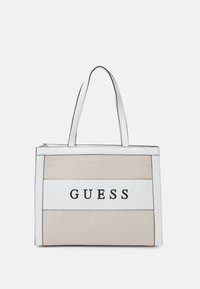 Torba na ramię z beżowego materiału z białymi akcentami. Posiada dwa paski na ramię oraz wyraźne czarne logo "GUESS" z przodu.