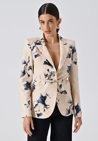 Bloemige blazer in roomkleur met marineblauwe botanische patronen, voorzien van een sluiting met één knop en een tailleband. Glad materiaal, gestructureerde silhoutte.