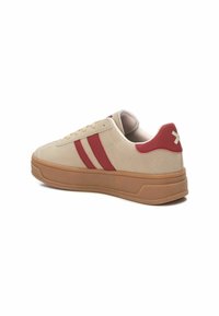 Sneaker beige in suede con strisce rosse e accento sul tallone, dotata di suola in gomma e collarino imbottito per il comfort.