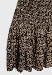 Tissu marron foncé avec motif floral de feuilles beige, comprenant une section supérieure froncée et un ourlet à volant froncé.