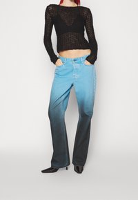 Černý pletený crop top a gradientní džínsy modro-černé. Džínsy mají rovný střih, pět kapes a kontrastní švy. Podpatky jsou černé.