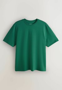 T-shirt en coton vert foncé uni à manches courtes et col rond, suspendu sur un fond clair, affichant la vue de face.