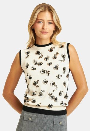 Top senza maniche di maglia crema con rifiniture nere, caratterizzato da applicazioni floreali in paillettes nei toni del argento e del nero per texture e dettagli.