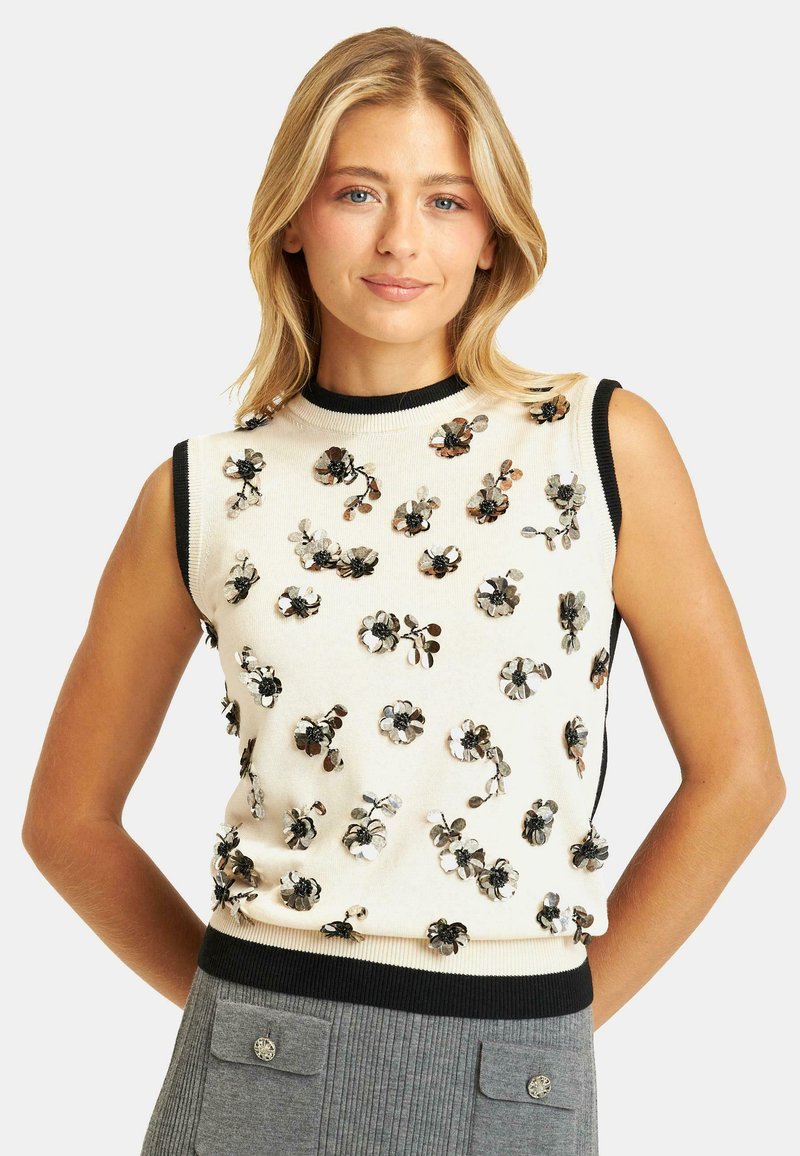 Top senza maniche di maglia crema con rifiniture nere, caratterizzato da applicazioni floreali in paillettes nei toni del argento e del nero per texture e dettagli.