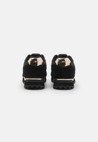Sorte semskede sneakers med metallisk gullhæl og aksenter, med teksturert såle og polstret krage for komfort.