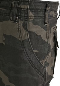 Bermudas cargo con patrón de camuflaje en tela de color verde oscuro y gris. Presentan bolsillos laterales y costuras reforzadas a lo largo de la cinturilla y las costuras.