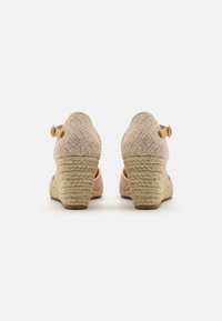 Sandalové wedges s textúrovaným béžovým zvrškom, ružovými akcentmi a tkaným lanovým podpätkom. Nastaviteľný detail s prackou na členku.