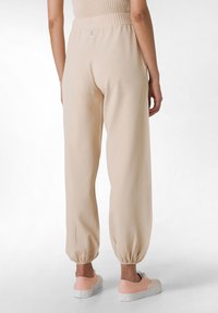Beige Jogginghosen mit lockerer Passform, elastischem Bund und schmal zulaufenden Säumen. Eine Kombination aus lässigem Stil und Komfort. Leichtes Baumwollmischgewebe.