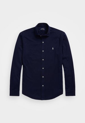 Navyblå langærmet skjorte med knapper, krave og lille hvidt broderet logo på venstre bryst.