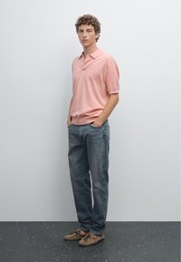Ljust rosa polo med korta ärmar, parat med ljusblå jeans och beige mockaskor. Enkel design, avslappnad passform.