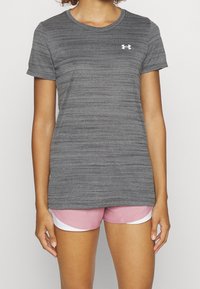 Grå atletisk t-shirt med korte ærmer, subtil stribet tekstur og lille hvidt logo. Matcher med lyserøde shorts med hvide detaljer.