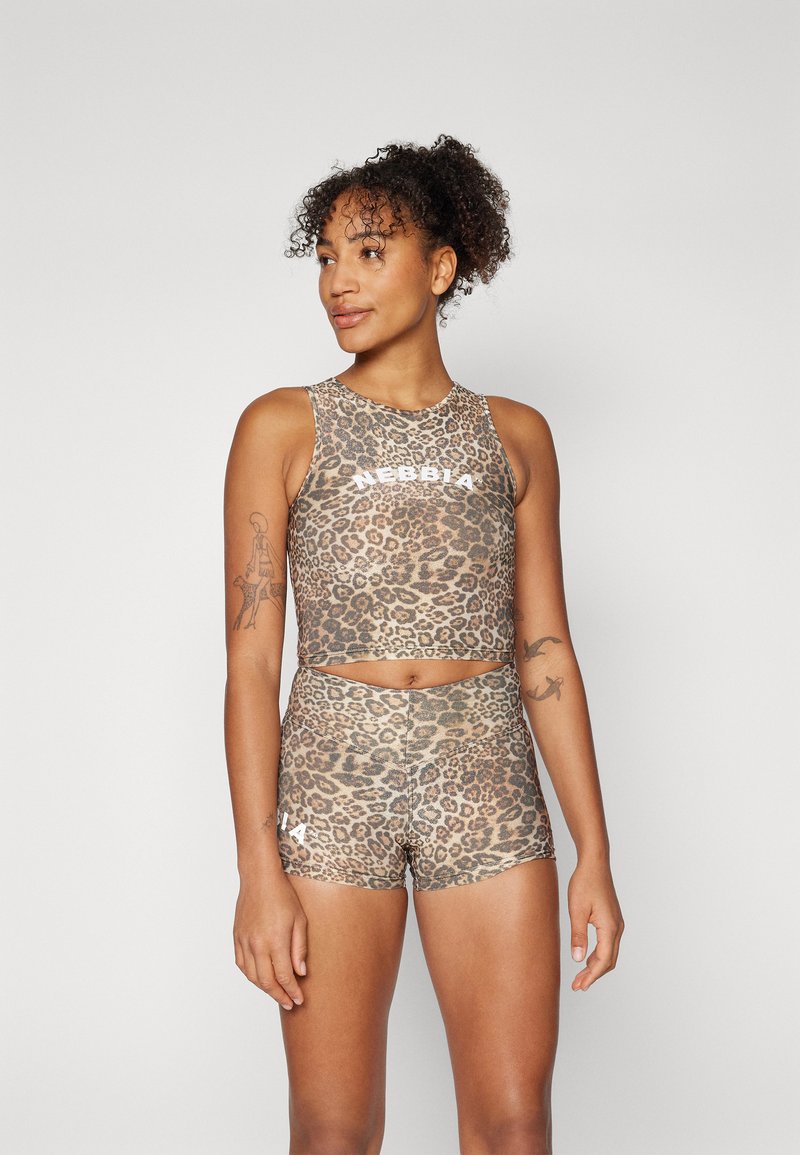 Top sportivo corto con stampa leopardata e pantaloni corti a vita alta in toni naturali. Il materiale è elasticizzato con una texture liscia e presenta un marchio bianco.