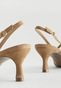 Ruske suede cipele s remenom oko pete i konusnim potpeticom, s uskim remenom oko gležnja i metalnim detaljem kopče. Glatki unutarnji oblog.