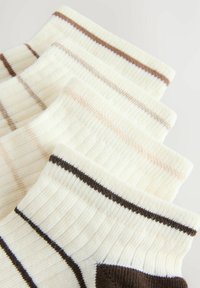 Cinq paires de chaussettes blanches côtelées avec des rayures de différentes couleurs, alignées sur un fond clair.