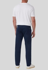 Navyblauwe chino's van katoen, met een rechte pijp, twee achterzakken en een tailleband met riemlussen. Gecombineerd met een wit t-shirt.