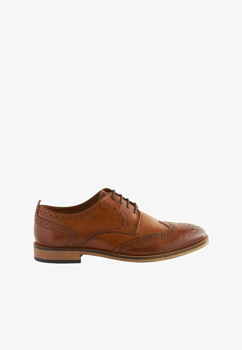 Brown leather dress shoe with wingtip design, perforated detailing, and a low stacked heel. Lace-up closure and smooth texture.