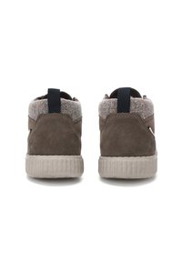 Een paar bruine suède sneakers met een grijze stoffen kraag en zwarte hiellooplippen, vanuit de achterkant gezien op een witte achtergrond.