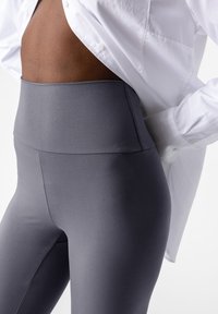 Leggings grigi alti in vita realizzati in un materiale liscio e elastico, con un design senza cuciture e dettagli di cucitura minimi.