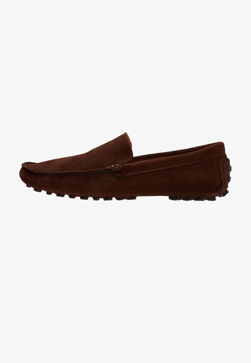 Mocassin de conduite en daim marron foncé avec semelle cloutée en caoutchouc et couture style mocassin sur le côté.