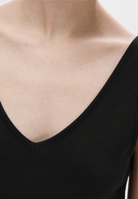 Černý žebrovaný top s hlubokým V-výstřihem, jemně prošitými okraji a těsným střihem. Materiál se zdá být měkký a elastický.