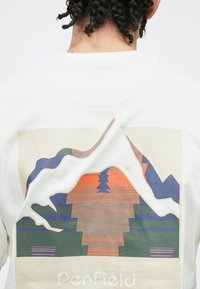 Valge T-särk, millel on maatoonides mägede ja puude graafiline kujundus erksate aksentidega. Alumises osas on tekst "Penfield".