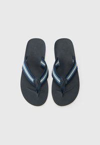 Tumedad flip-flops, millel punkti sinise ja valge tooni sanga, tekstuuriga jalapadja ja tasase tallaga. Brandi logo on nähtav sangal.