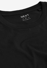 T-shirt en coton noir avec un col rond et des manches courtes. L'étiquette affiche "NEXT", "M" et "REGULAR FIT" en texte blanc. Texture lisse.