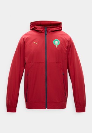 Jachetă roșie cu glugă și fermoar complet, cu emblema echipei de fotbal din Maroc pe piept și logo-ul Puma auriu pe partea dreaptă.