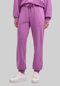 Fioletowe spodnie dresowe z elastycznym pasem i regulowanym troczkiem. Posiadają dwie boczne kieszenie oraz ściągacze przy nogawkach.