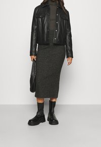 Veste en cuir noir sur une robe midi tricotée gris foncé. Des bottes noires épaisses et un sac noir complètent l'ensemble. Design simple, sans motifs.