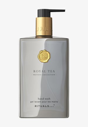 Bouteille de savon liquide rectangulaire et transparente avec une finition mate. Pompe dorée et emblème. Texte noir sur le devant. Design simpliste et moderne.