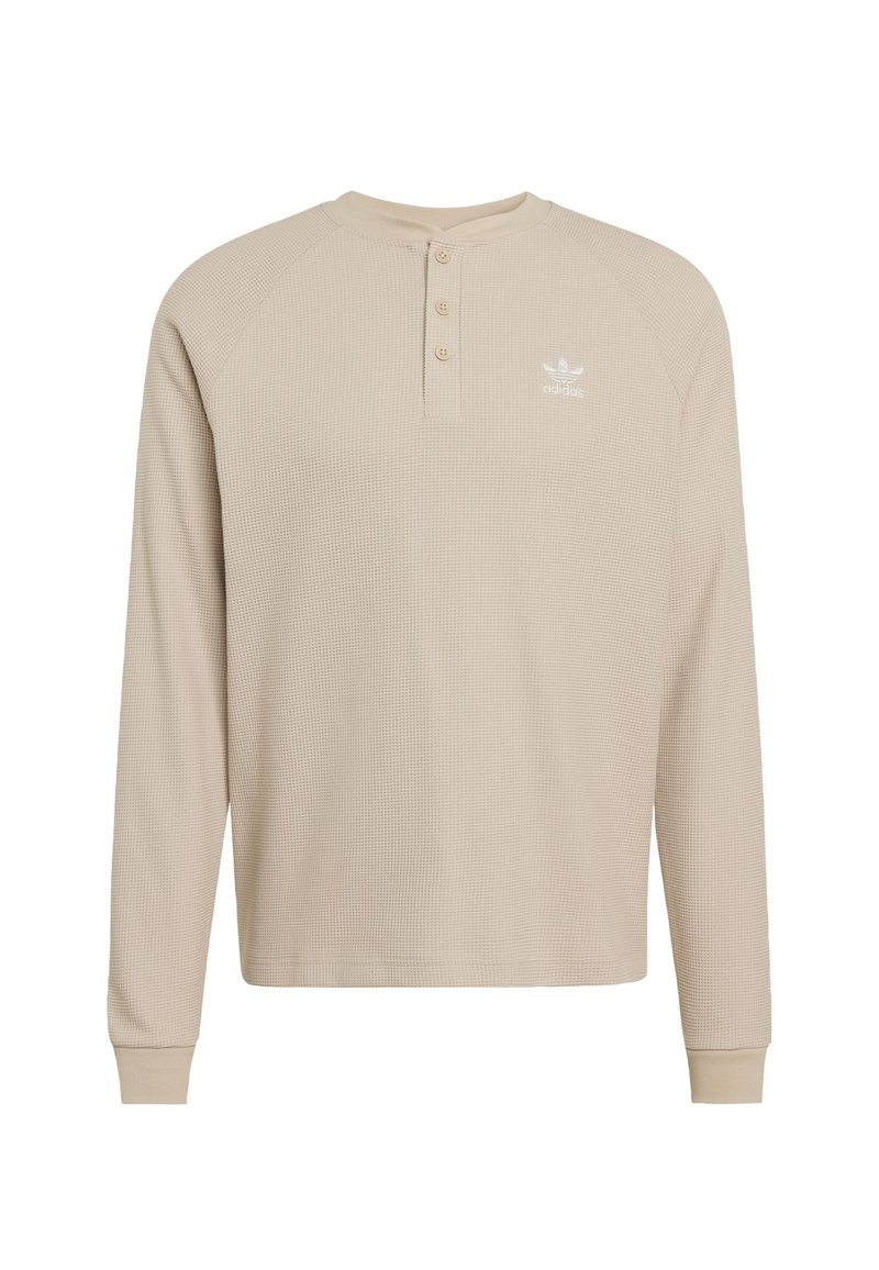 Beige long-sleeve henley shirt with textured fabric, three-button placket, and white logo on the left chest. Ribbed cuffs and collar.