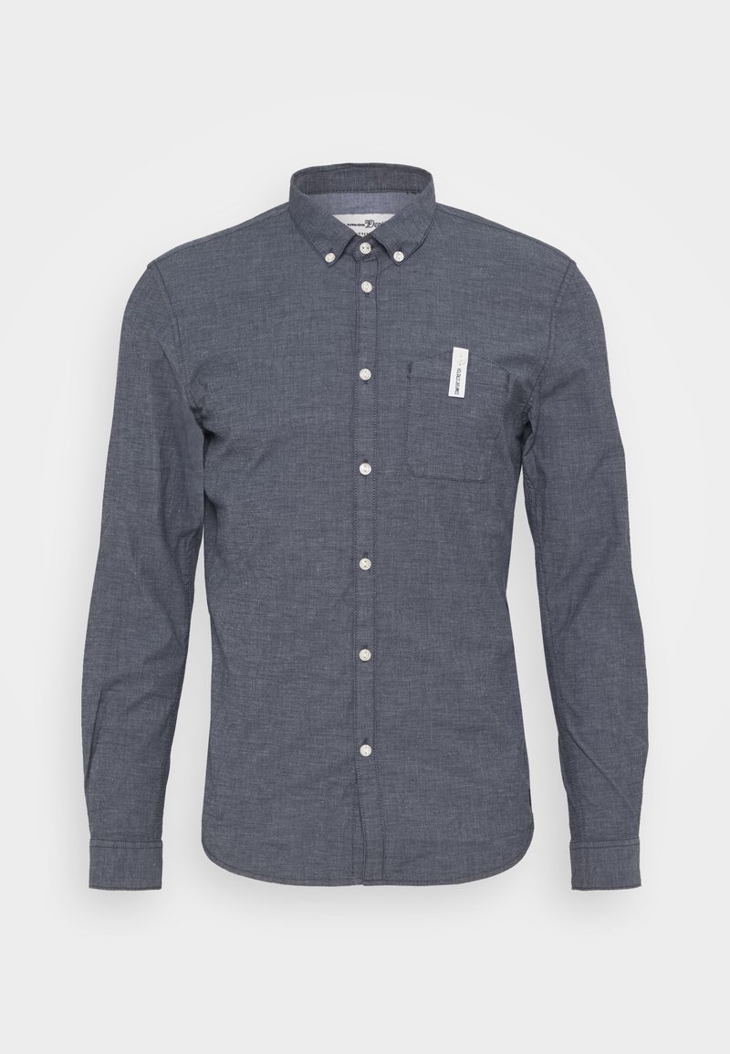 Camisa de botón azul oscuro hecha de una tela texturada, con un bolsillo en el pecho y botones blancos en la parte delantera. Diseño de cuello clásico.