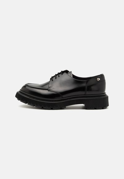 Pantofi din piele neagră cu un finisaj neted, cu vârf rotunjit și sistem de șireturi. Prezintă o talpă groasă, texturată, cu nervuri și un accent decorativ.