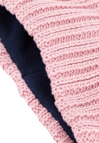 Bonnet tricoté avec un extérieur rose clair et une texture côtelée, accompagné d'une doublure en polaire douce bleu marine. Mettez l'accent sur le contraste des matériaux et les détails.