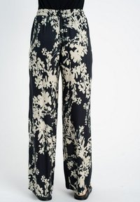 Spodnie o szerokich nogawkach z czarno-kremowym kwiatowym wzorem, z elastycznym paskiem w talii, wykonane z gładkiego, lekkiego materiału. Posiadają luźny krój.